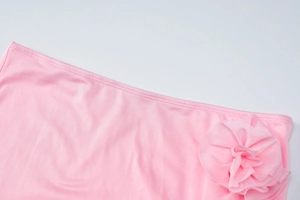 Detail of pink knitted fabric featuring handmade floral decoration and precise stitching