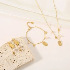 Detail of gold necklace and bracelet set with stars, pearls and coin pendants