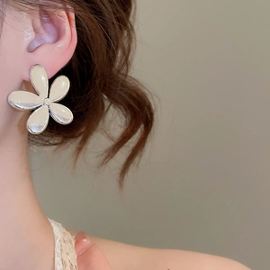 Gros plan d'une boucle d'oreille en argent en forme de fleur à cinq pétales sur l'oreille