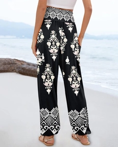 Rear view of women's high-waisted floral wide-leg trousers on a beach background