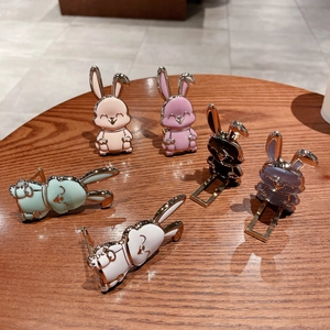 Soportes de metal para móvil con forma de conejo en varios colores sobre madera