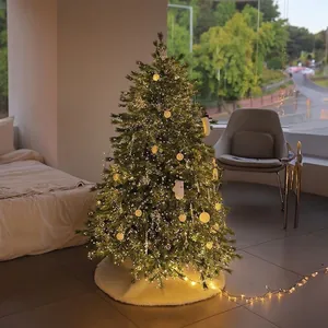 Lush artificial Christmas tree with warm LED lights and white faux fur plush tree skirt
