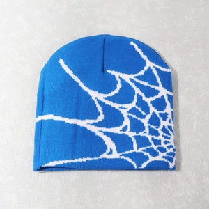 Close-up of blue knitted beanie featuring white spider web pattern and woven texture