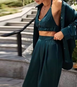 Dettaglio di un completo tre pezzi in raso verde scuro con crop top e pantaloni
