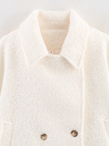 Close-up of cream bouclé coat collar with tortoiseshell buttons and size S tag