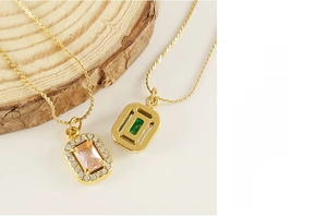 Macro detail of gold double-layer necklace with pink and green zircon square pendants