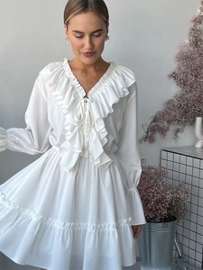 Detail of V-neck white chiffon dress featuring delicate ruffles and lace-up ties