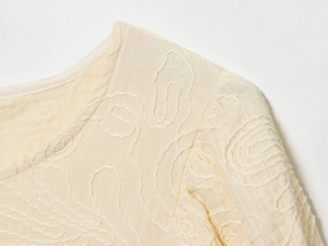 Vue macro des détails délicats de broderie beige sur un tissu texturé respirant