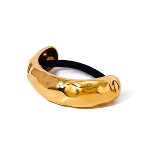 Golden textured metal hair cuff with black elastic tie on a clean white background
