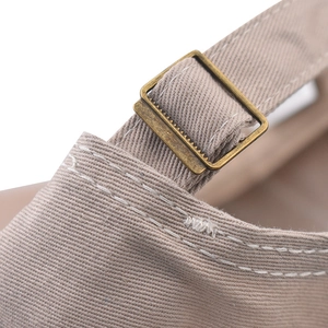 Detailed close-up of a vintage metal buckle and beige twill fabric on a baseball cap