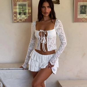 Detailed view of white floral lace fabric on a hollow-out long sleeve top and tiered skirt