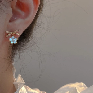 Elegantes pendientes de lazo y flor dorados con perlas en modelo para un look suave