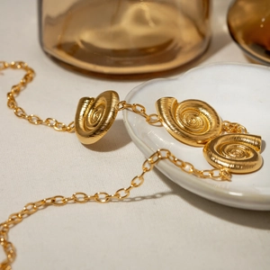 Elegant 18k gold stainless steel necklace with three spiral rings on a white fabric background