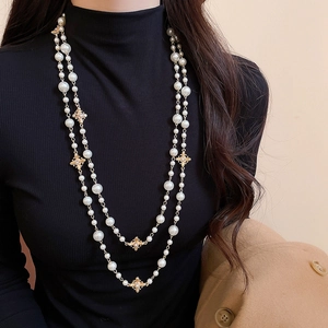 Close-up of vintage double-layer pearl necklace with golden cross charms on black sweater