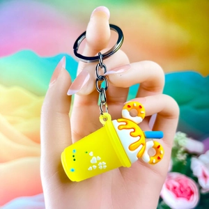 Close-up of a yellow ice cream cup keychain with donuts and a blue straw