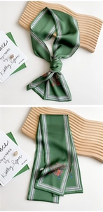Detailed view of dark green silk scarf with horse saddle prints and geometric edges
