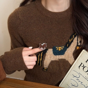 Nahaufnahme eines braunen Emaille-Schaukelpferd-Rings mit warmem Strickpullover