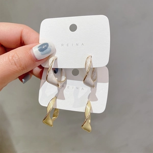 Detail showing twisted hoop earrings in white and light gold finishes with drip oil texture