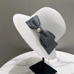 Elegant white straw hat with houndstooth bow and pearl detail on a metal display stand
