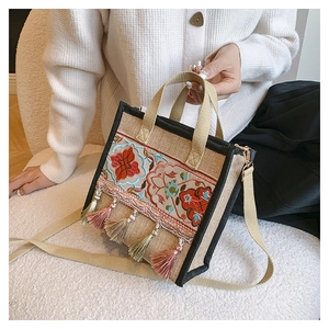 Close-up of ethnic embroidered tote bag featuring colorful tassels and linen texture