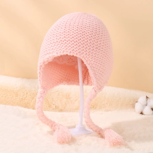 Detail of pink knitted baby hat with fleece lining, ear flaps and braided tassels