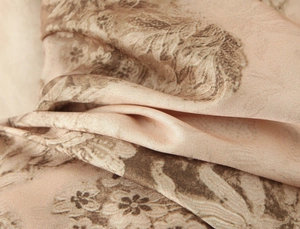 Close-up van beige satijnen bloemenstof met zachte plooien en zijdeachtige textuur