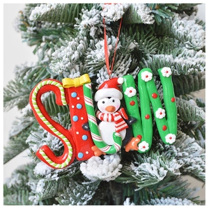 Detail of Snow penguin resin ornament hanging on a snowy Christmas tree branch