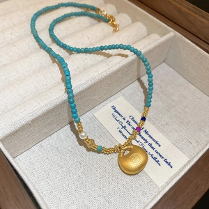 Détail de perles colorées avec perle d'eau douce et pendentif serrure dorée en coffret