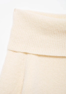 Macro shot of fine knit texture and stitching details on a cream off-shoulder sweater