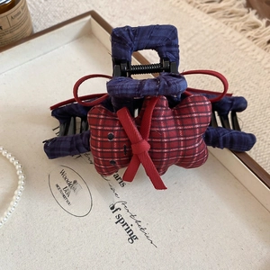 Detailed shot of dark blue plaid fabric bear hair claw clip with a red ribbon bow accessory