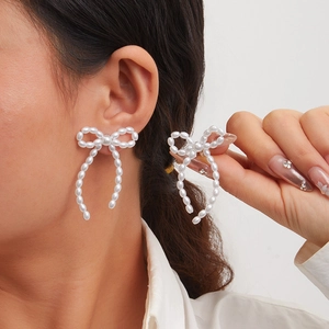 Close-up of elegant bow-shaped pearl tassel earrings worn by a model in soft lighting