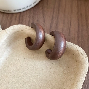 Gros plan de boucles d'oreilles pendantes en bois marron foncé ajouré style ethnique
