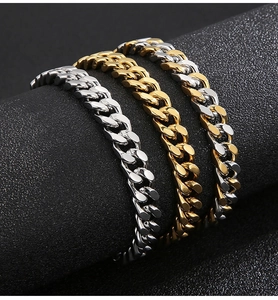 Close-up of polished stainless steel Cuban link bracelets in silver and gold finishes