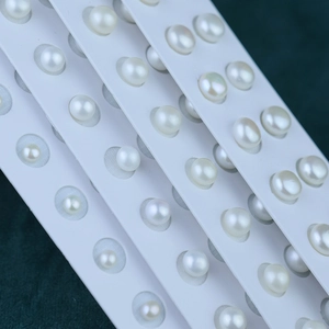 Multiple rows of natural white freshwater pearls in various sizes on a dark green base