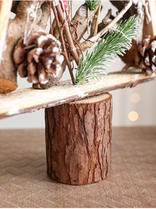 Close-up of rustic wooden Christmas tree detail with real pine cones and snow-dusted needles