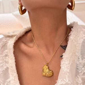 Detailed close-up of 18k gold-plated heart pendant and matching lava texture earrings