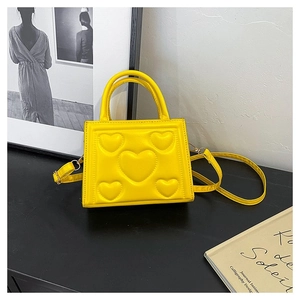 Détail d'un sac à main carré en cuir PU jaune avec motif cœur embossé et bandoulière