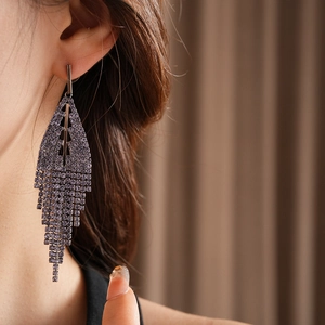 Detailed view of long silver fringe earrings with shimmering purple crystals and rhinestones