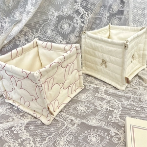 Detalle de cestas de tela acolchadas con bordado de conejo y aplique 3D sobre encaje