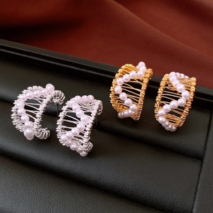 Detail of C-shaped 18k gold plated earrings with pearls on black leather display