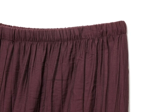 Detail view of burgundy skirt showing elastic waistband and fine pleated fabric texture