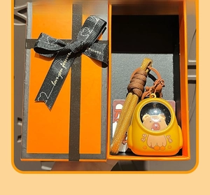 Cute Capybara backpack keychain in an orange gift box with black ribbon and bow