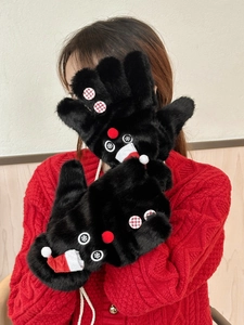 Detail of plush black mittens with Christmas snowman decor and a red knit background