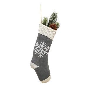 Detail of grey knitted Christmas stocking with white snowflake patterns and top hanging loop