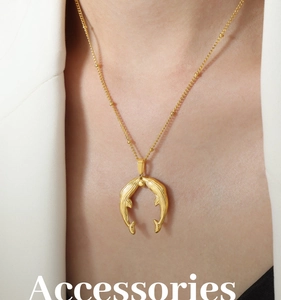 Detail of whale pendant necklace with gold beaded chain worn by a model in a white blazer