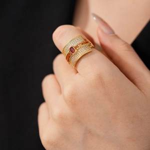 Detailed macro view of a luxury gold band ring with red stones and zircon pavé