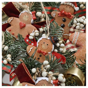 Festive gingerbread man ornament with red bow, bells and pine branches detail