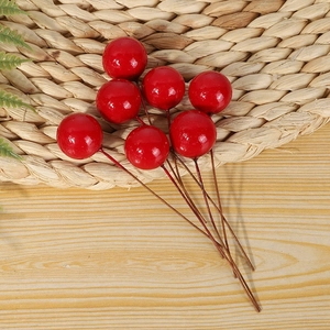 Détail de baies rouges artificielles brillantes sur tiges brunes pour décor de Noël