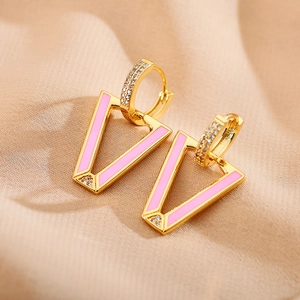 Macro shot of V-shaped pink enamel drop earrings with sparkling zircon inlay details