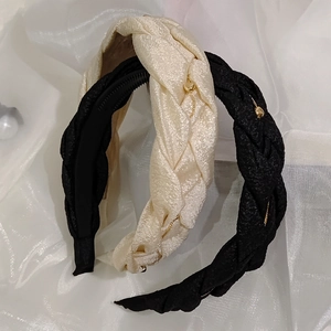 Close-up of woven hairbands in beige and black with golden bead details and anti-slip teeth